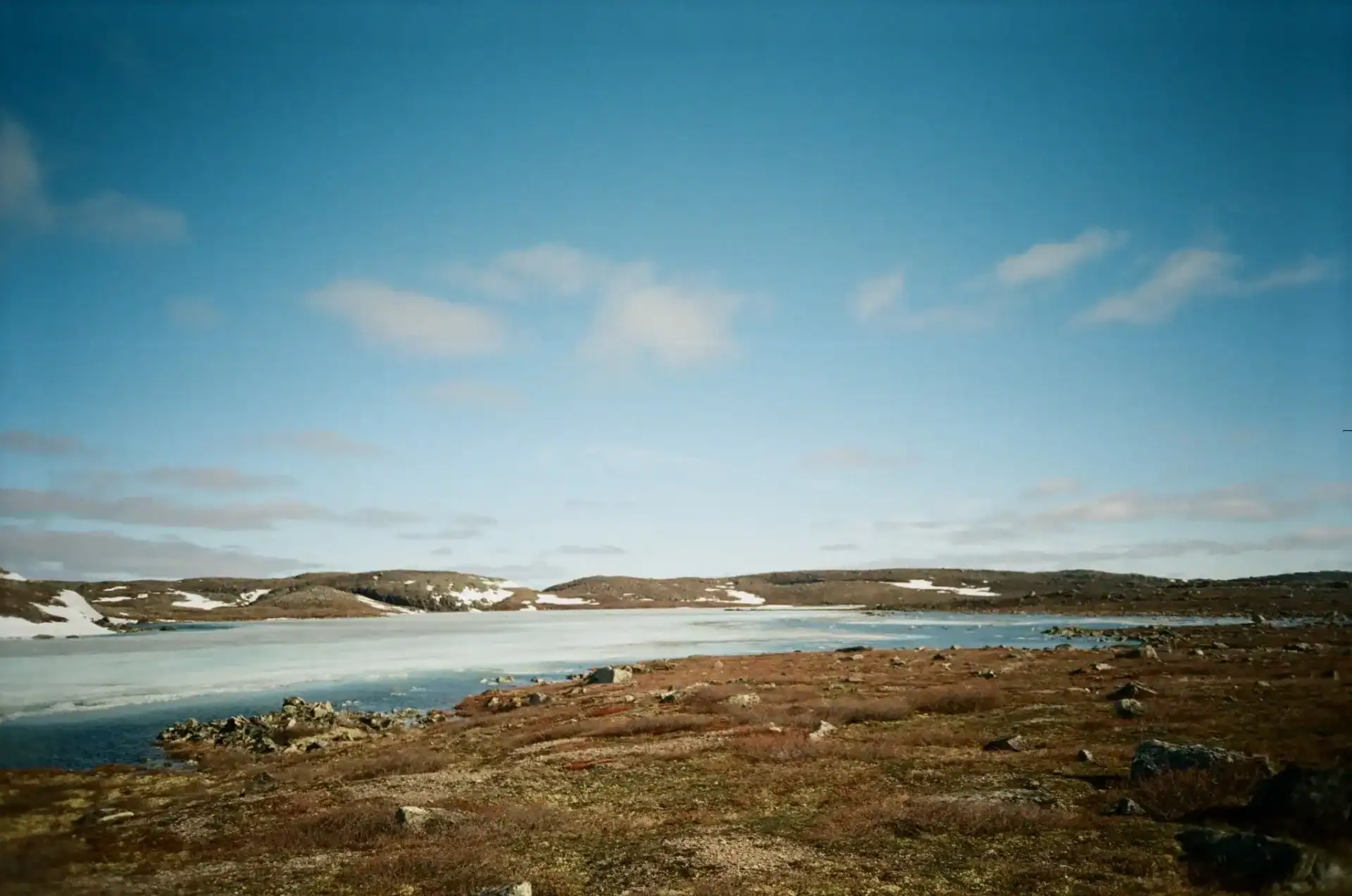 Expansive northern tundra and lake beneath a dramatic sky